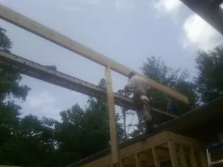 Carpenter setting a ridge beam over a new addition frame — Ice Dam Removal by Roofing Brothers in Raymondville