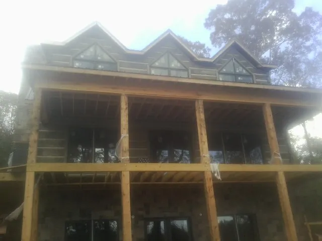 Dormers and porch framing on a large log home under construction — Roof Coating work by our crew in Raymondville
