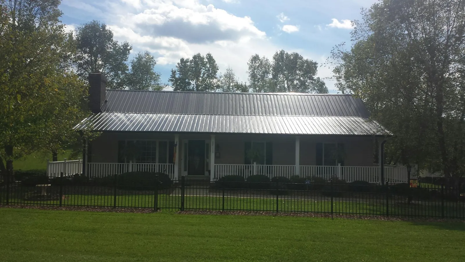 Gray metal roof on a brick ranch with a full width front porch — Gutter Guard Installation work by our crew in Raymondville