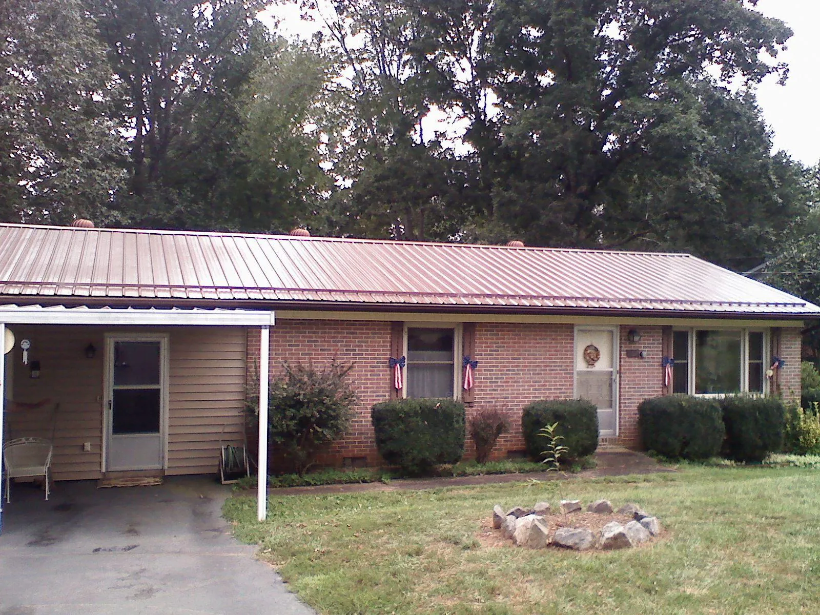 Bronze metal roof and carport on a brick ranch home — Roof Repair work by our crew in Raymondville