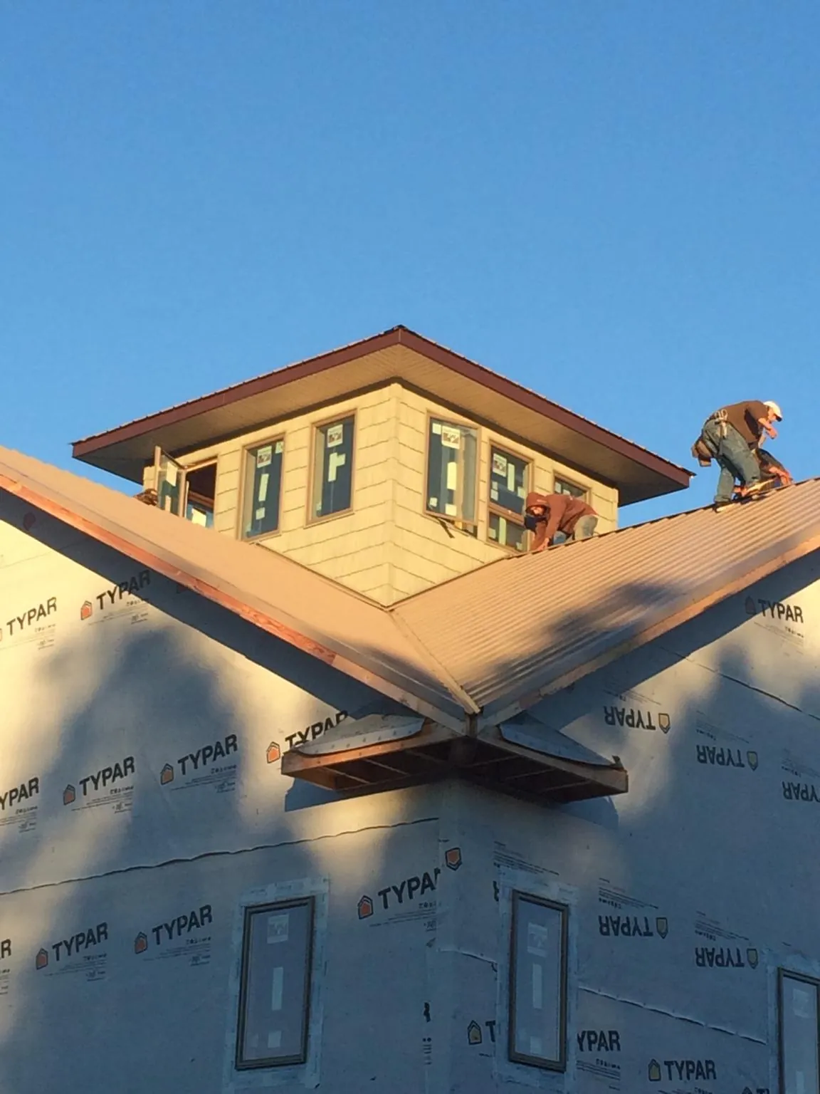 Roofers working around a rooftop cupola on a new metal roof at sunset — Roof Waterproofing in Raymondville by Roofing Brothers